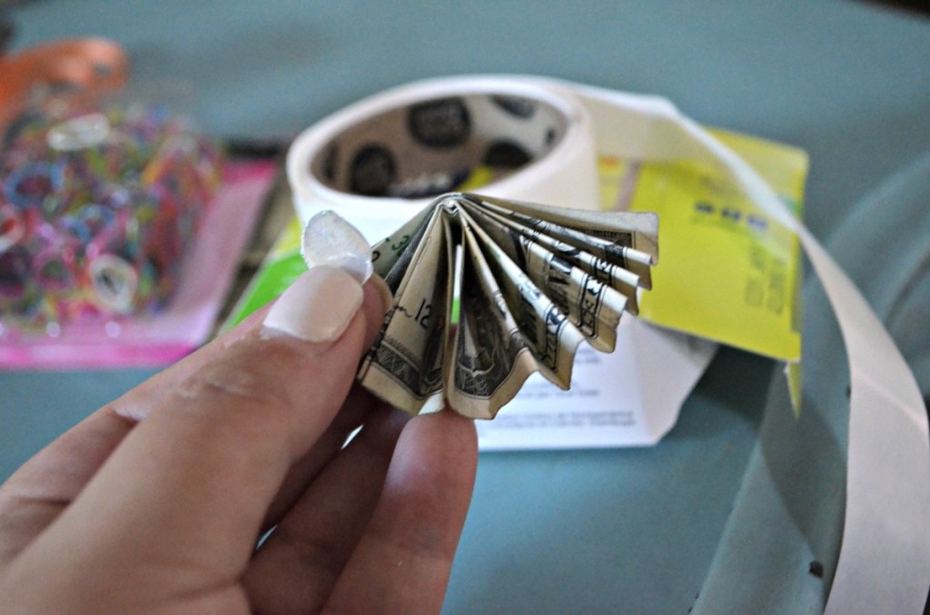 holding a dollar bill folded accordion style