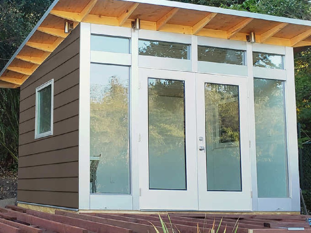 small house with windows and glass doors by trees