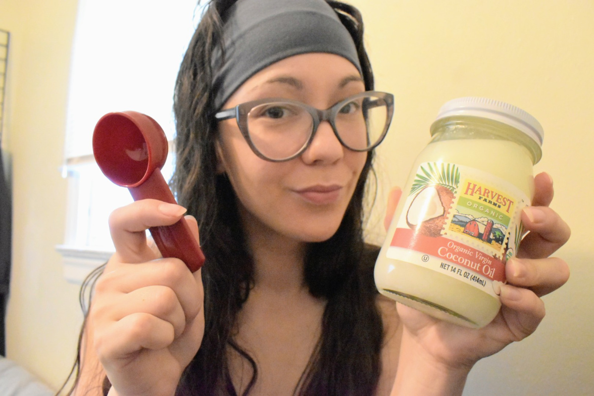 woman holding jar of coconut oil and tablespoon