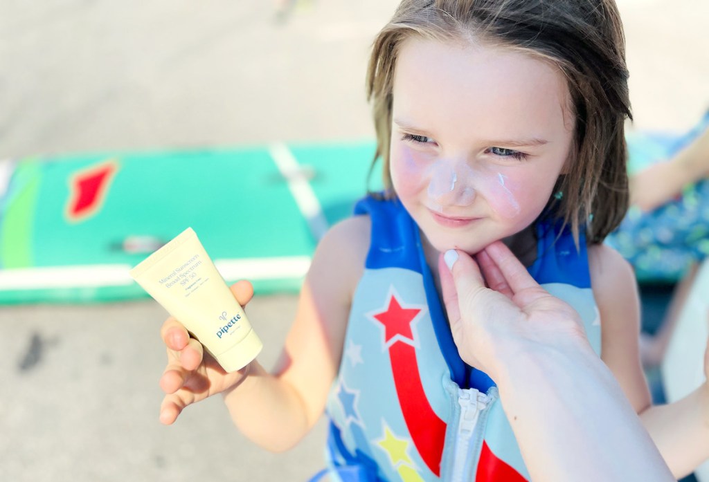 girl holding bottle of pipette kids sunscreen