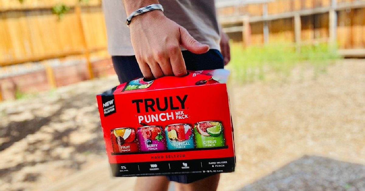 man holding a variety pack of hard seltzer standing outside in the sun