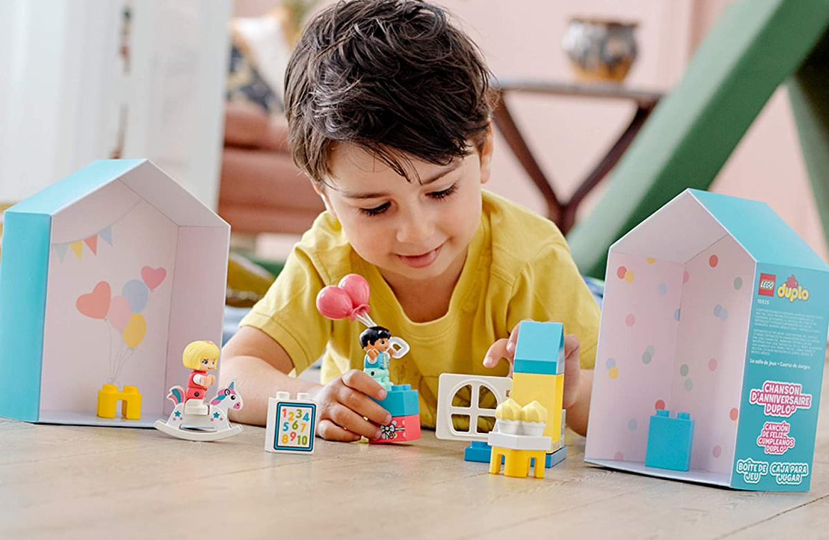 kid building a LEGO town playhouse set on table