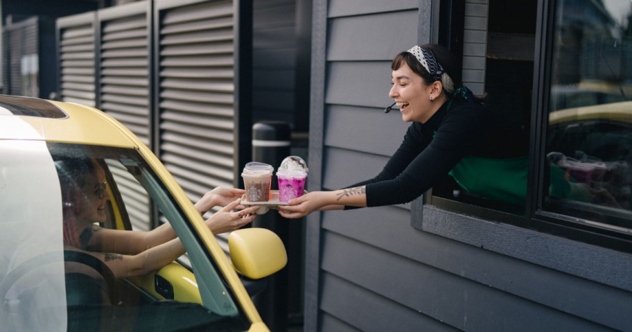 Barista handing drinks to care inStrabucks drive through