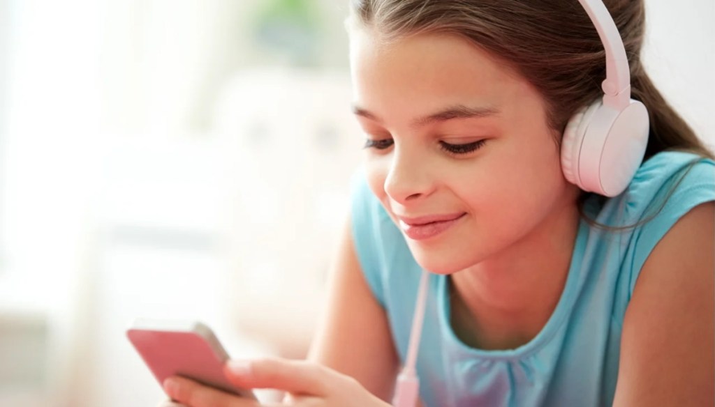 teen wearing headphones and looking at phone