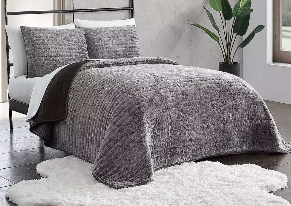 grey quilt and pillows on a bed