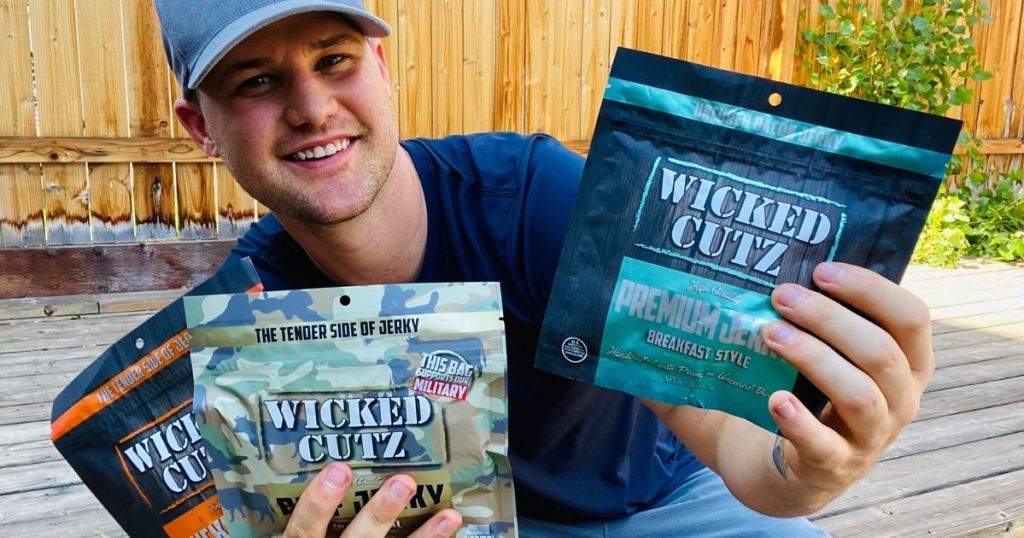 man holding three bags of jerky