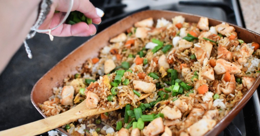 adding green onion to fried rice