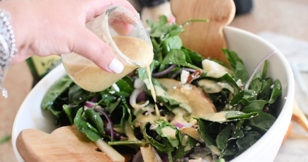 adding pear salad dressing to salad