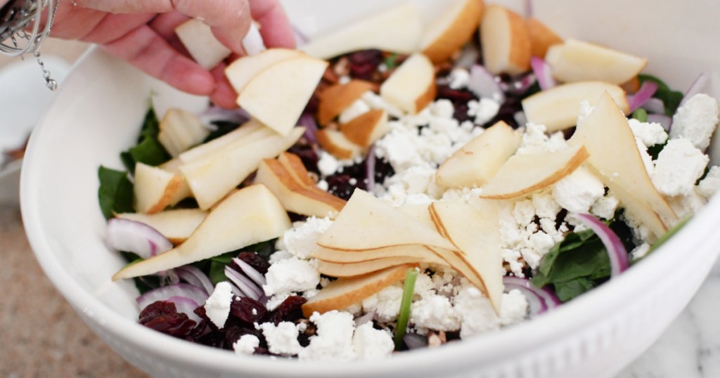 adding pears to spinach salad