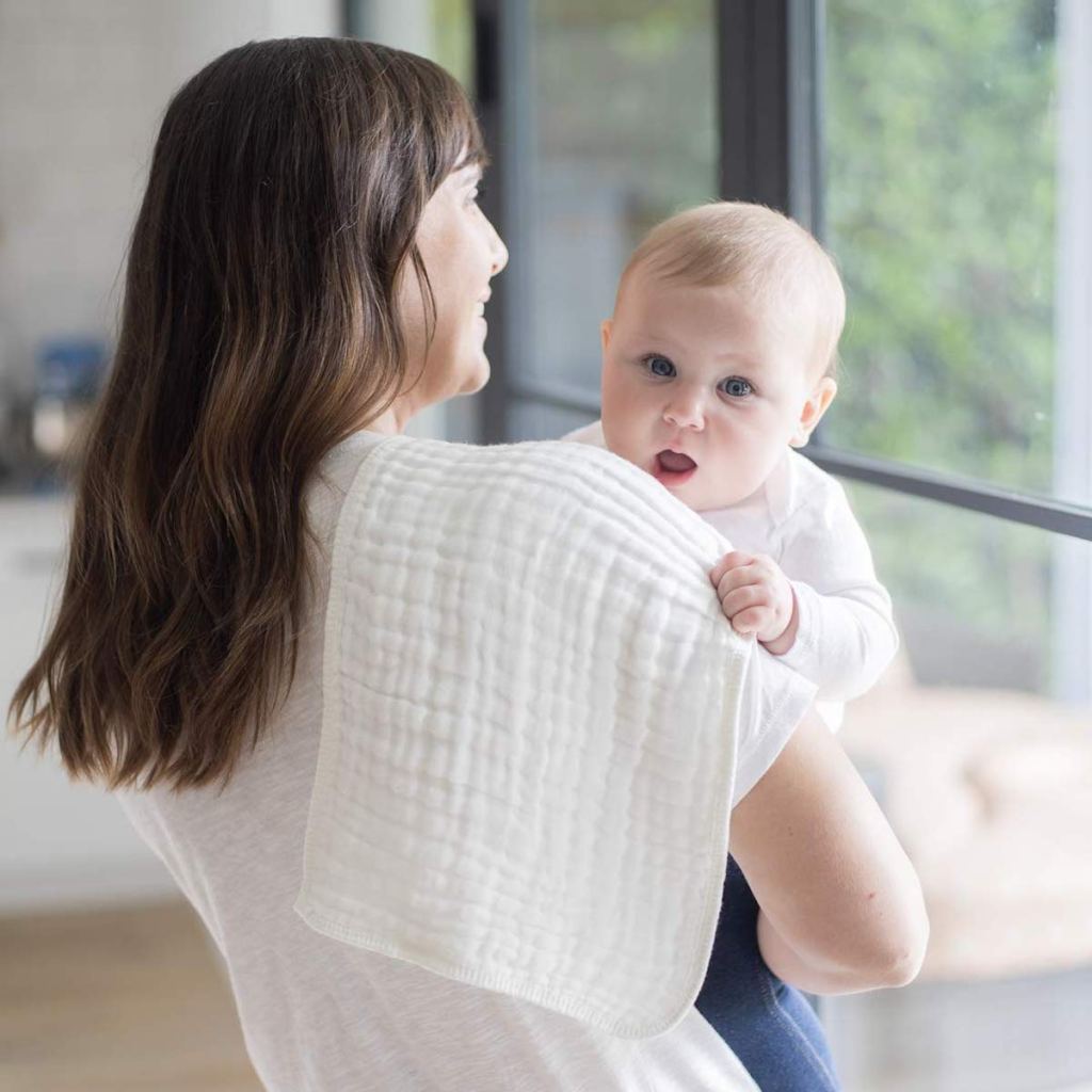 woman holding baby with white burp cloth on shoulder