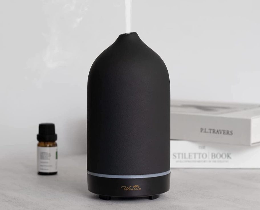 black stone essential oil diffuser on table with steam onlineing out of top