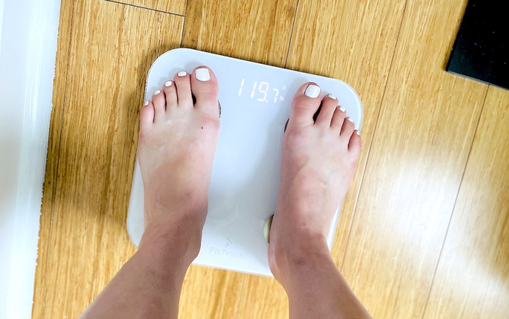 feet standing on top of white scale with weight at the top