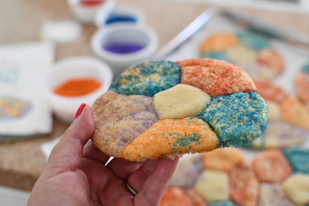 holding large flower cookie with sprinkles