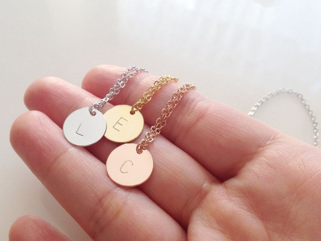 hand holding initial stamped necklace charms