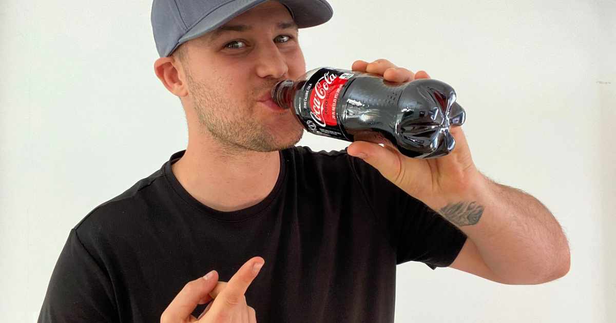 man holding coke bottle to mouth