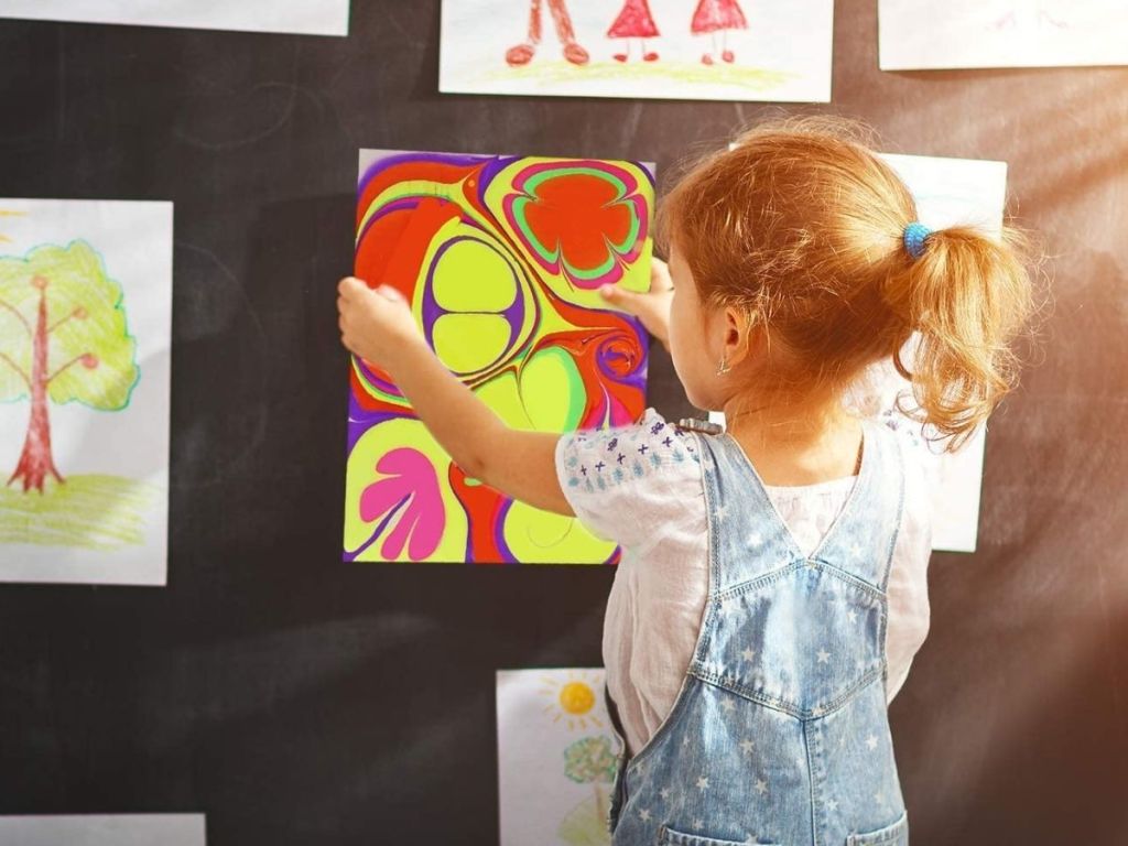 kid hanging up marble art work