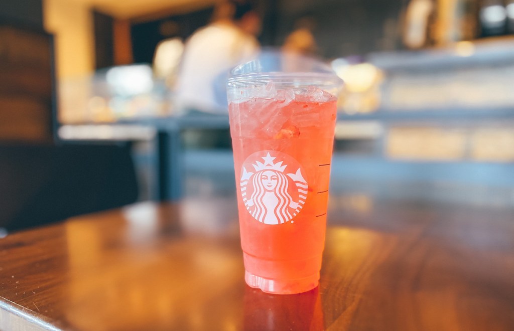 orange pink drink in starbucks cup on wood table