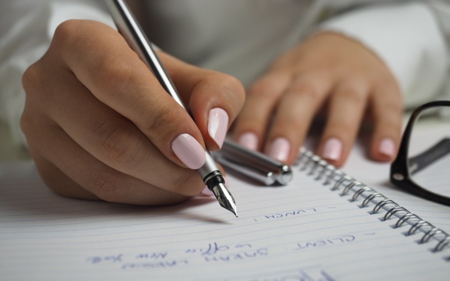 person writing a list, perhaps of unusual scholarships