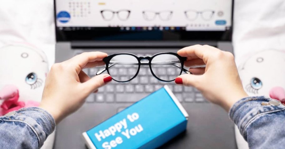 woman holding glasses in front of laptop with glassesusa pulled up on onlineputer