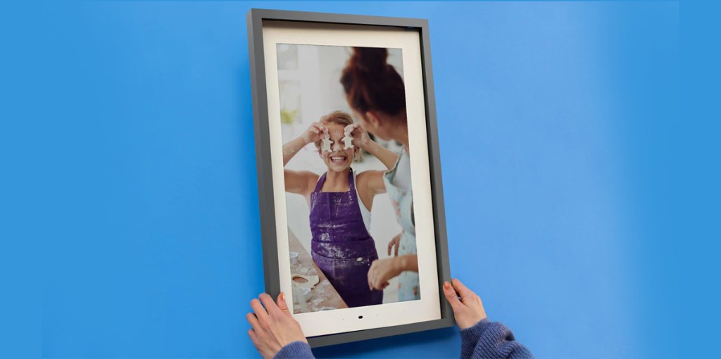 hand holding smart frame near blue wall