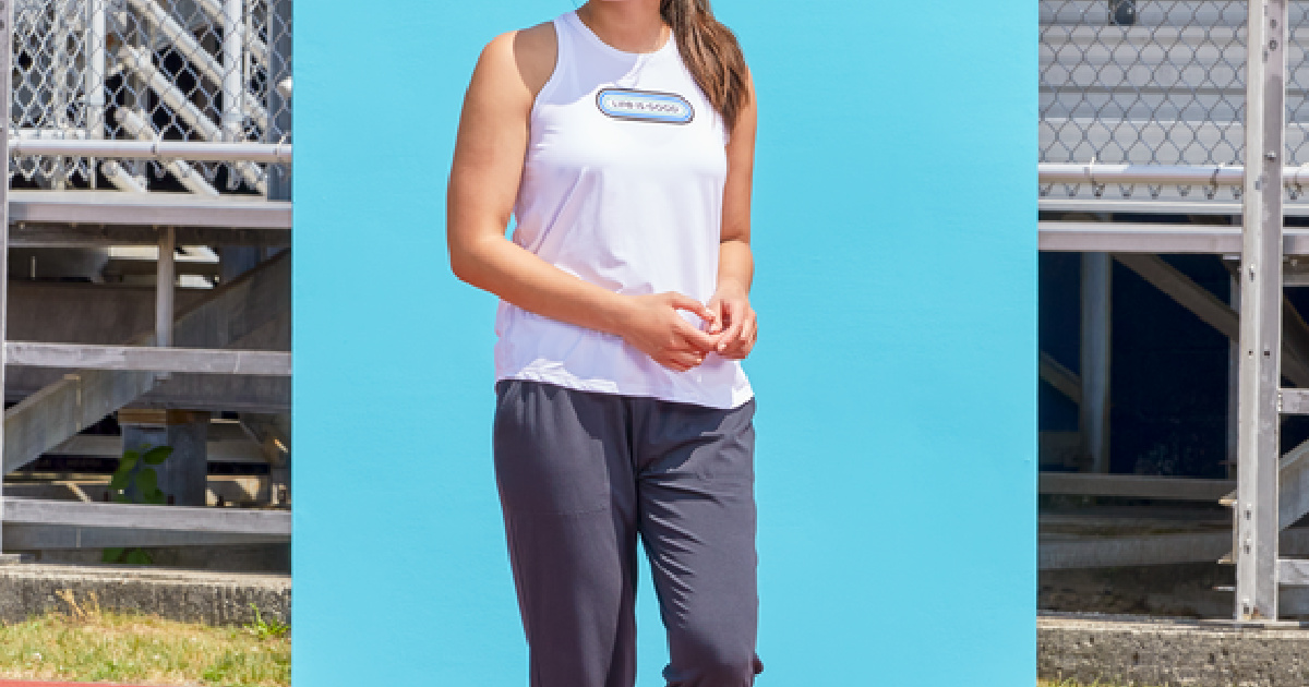 woman wearing a life is good tank top standing in front of a blue background