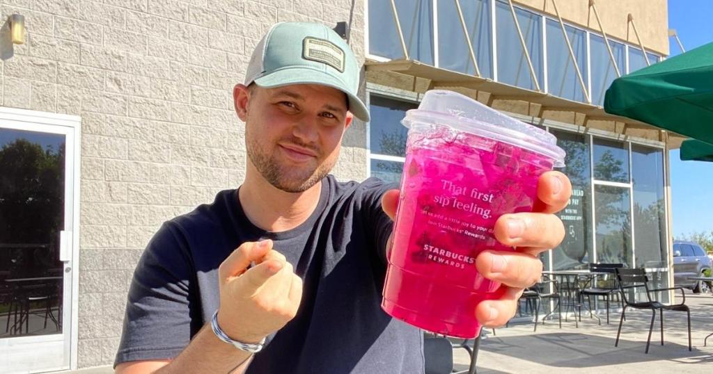 man holding starbucks refresher drink outside store