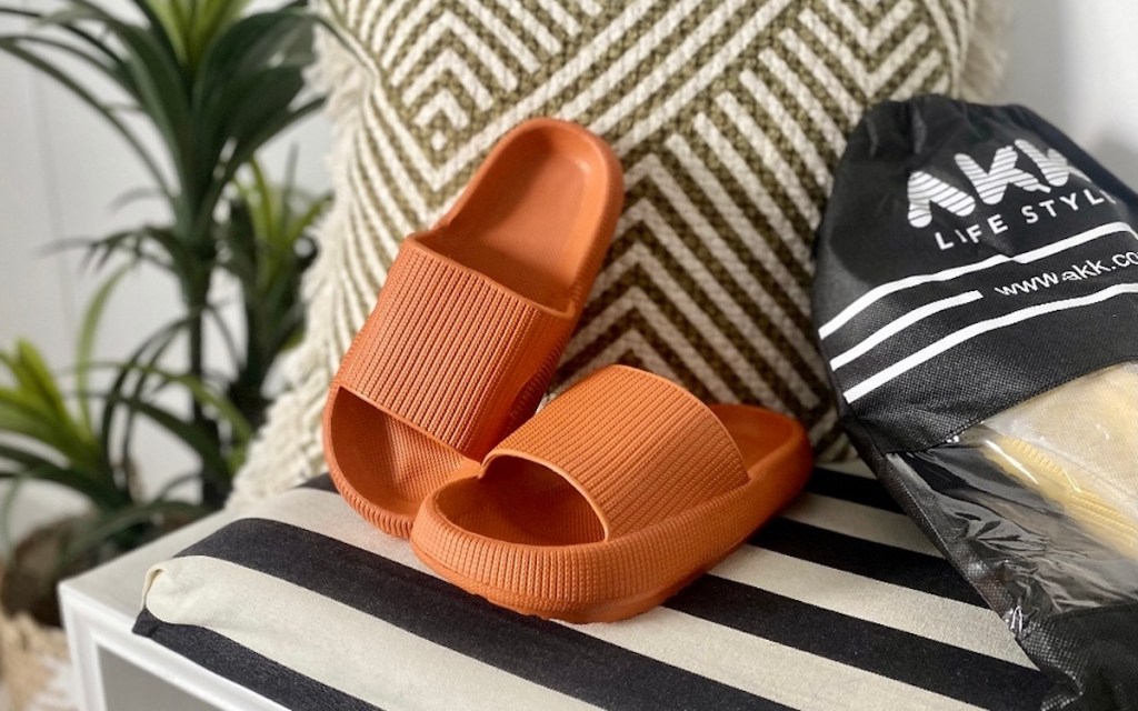 pair of orange bathroom slippers leaning on pillow