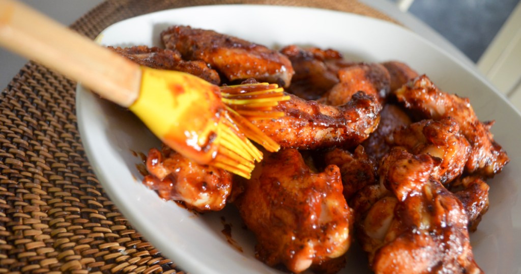 brushing sauce on baked honey chicken wings