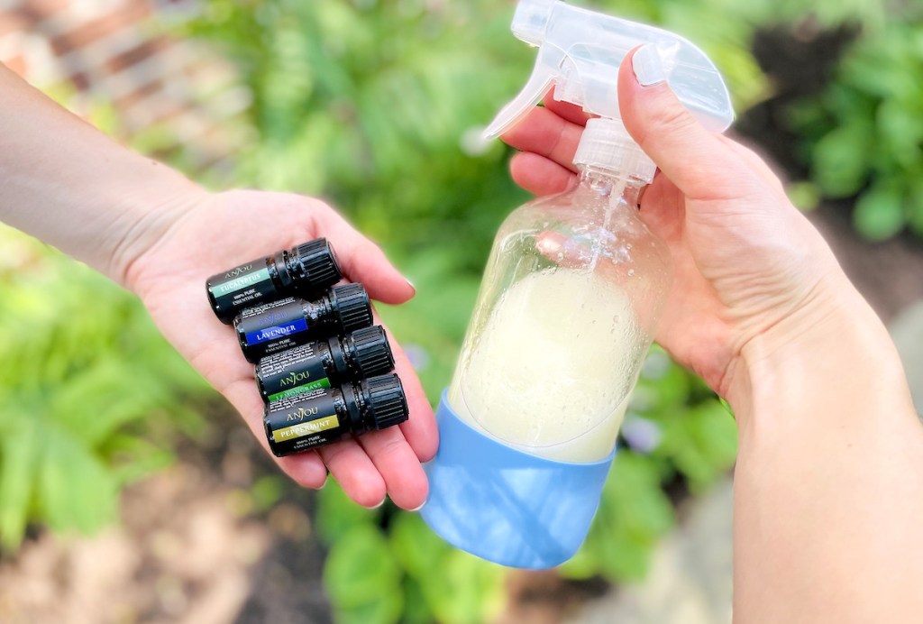 hands holding glass diy bug spray bottle and anjou essential oils