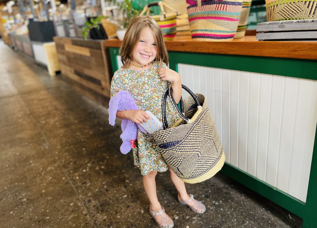 young girl holding market bag in store