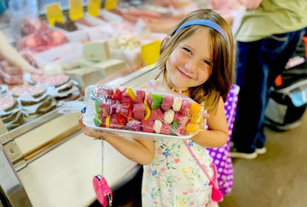 girl holding steak kabobs on tray 