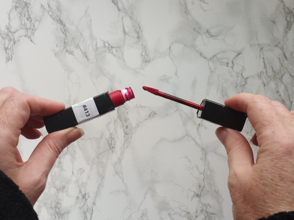 holding open tube of lipstick