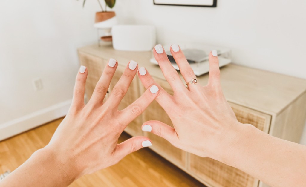 holding up hands in air with fingers spread apart in front on media table