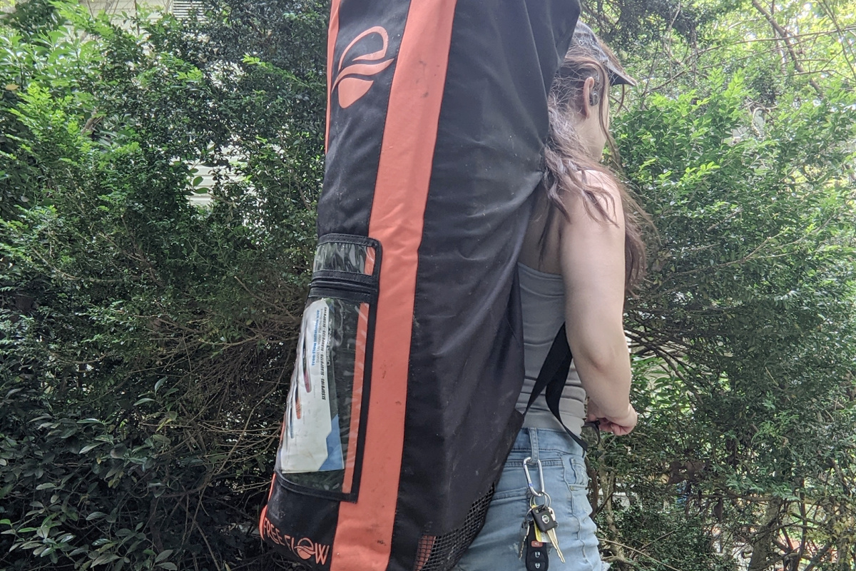 Woman carrying large backpack with inflatable paddle board inside