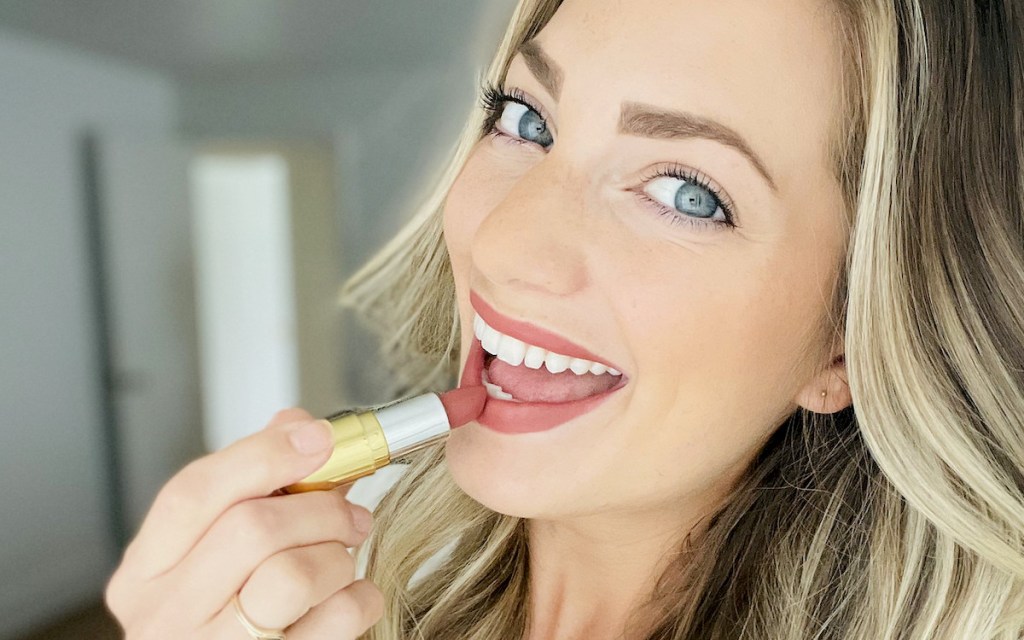 close up of woman putting on dark red lipstick