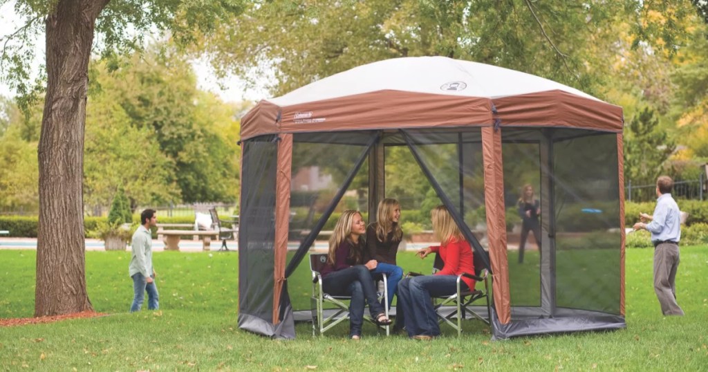 brown screened tent set up in yard with people