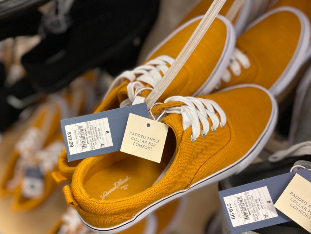 mustard colored sneakers on hanger on display in-store