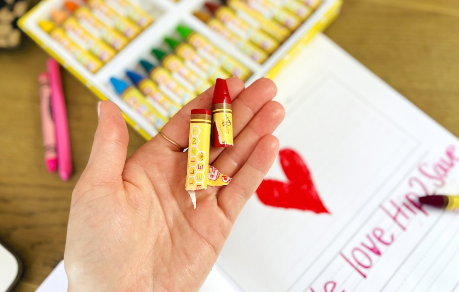 hand holding a brilliant bee red wax sticks over heart paper