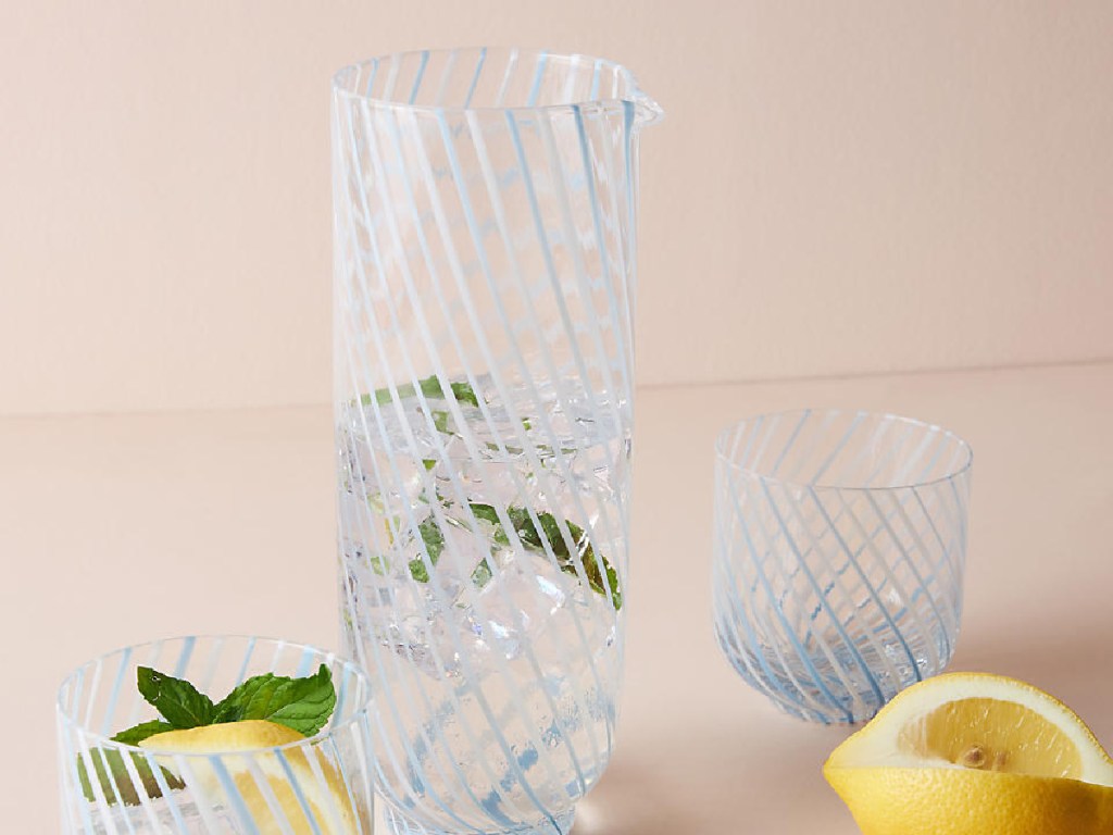 glass picther with water, lemons and glasses around it