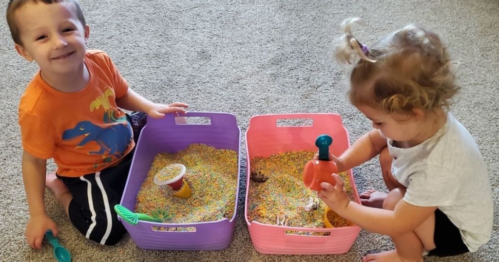 kids playing by purple and pink bins filled with colored rice and toys