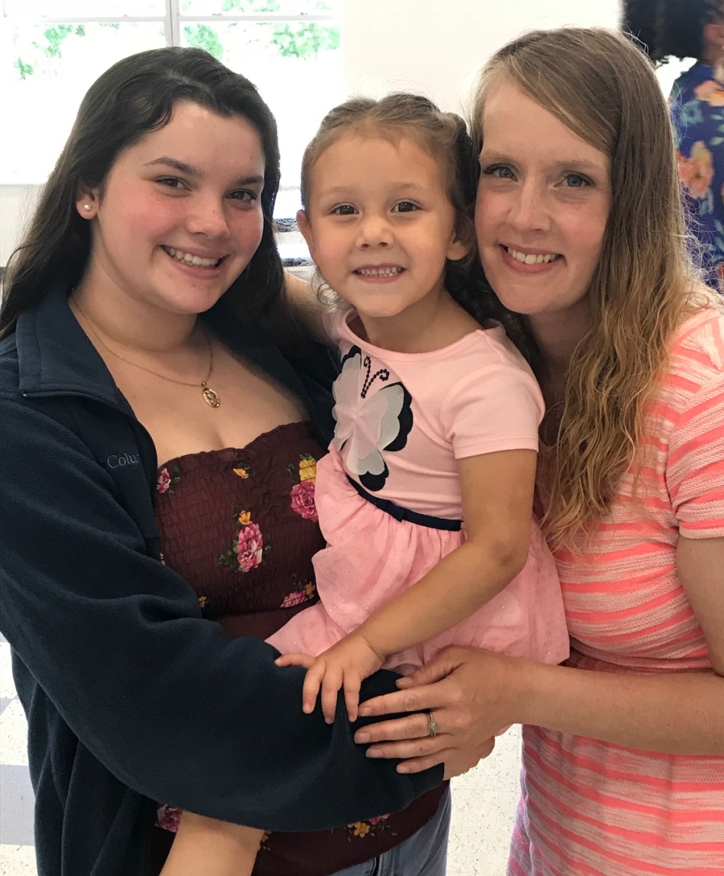 two woman holding young girl smiling at camera