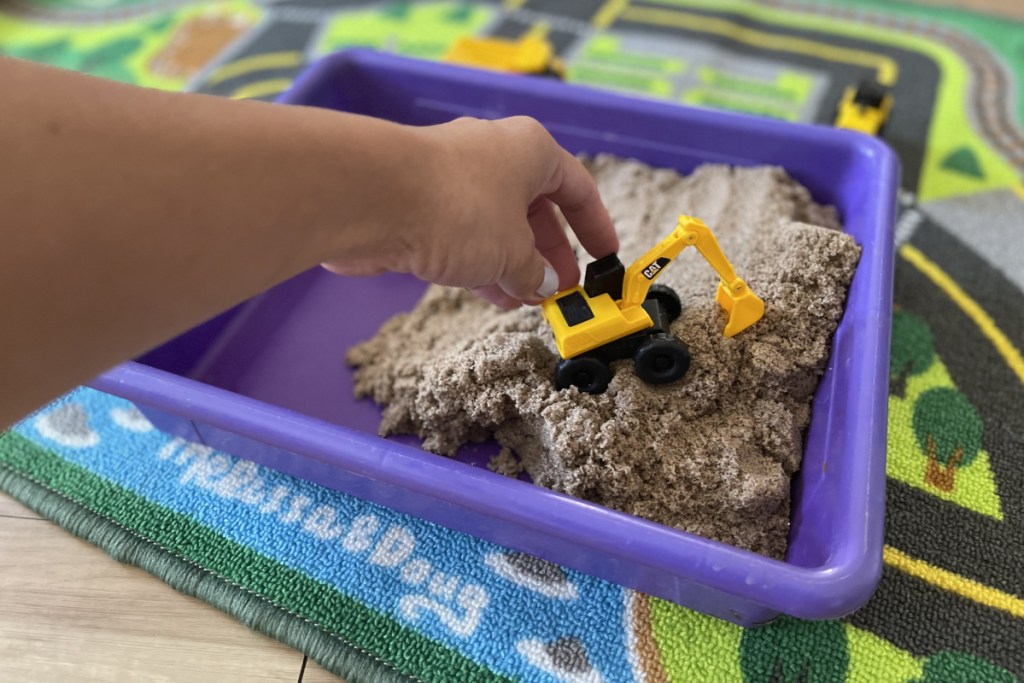 hand driving in kinetic sand construction pit