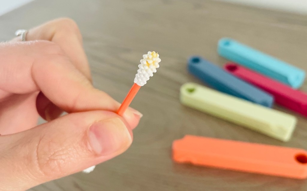 hand holding reusable q tip with ear wax on top