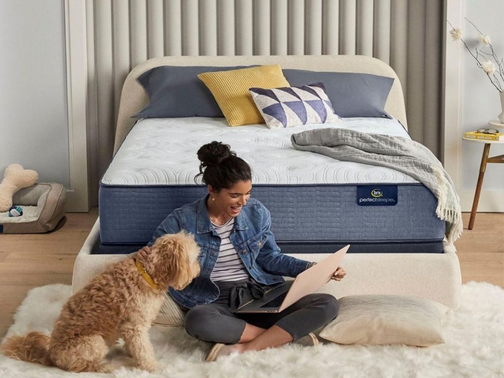 woman sitting in front of bed with dog