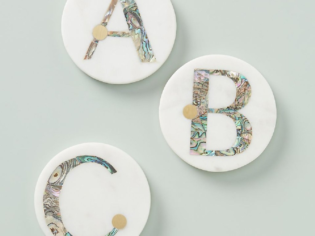 three coasters sitting on counter with letters on them