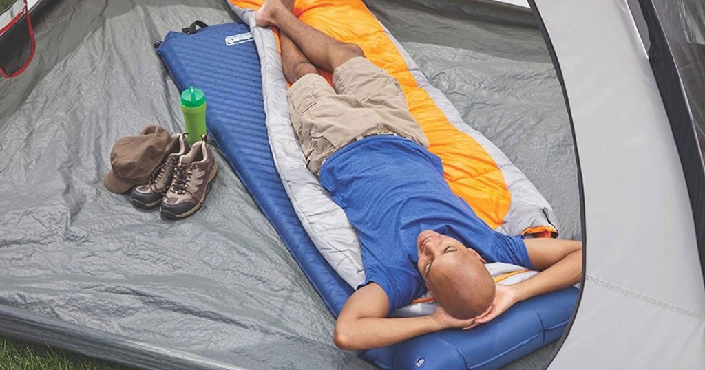 man laying on blue pad inside tent