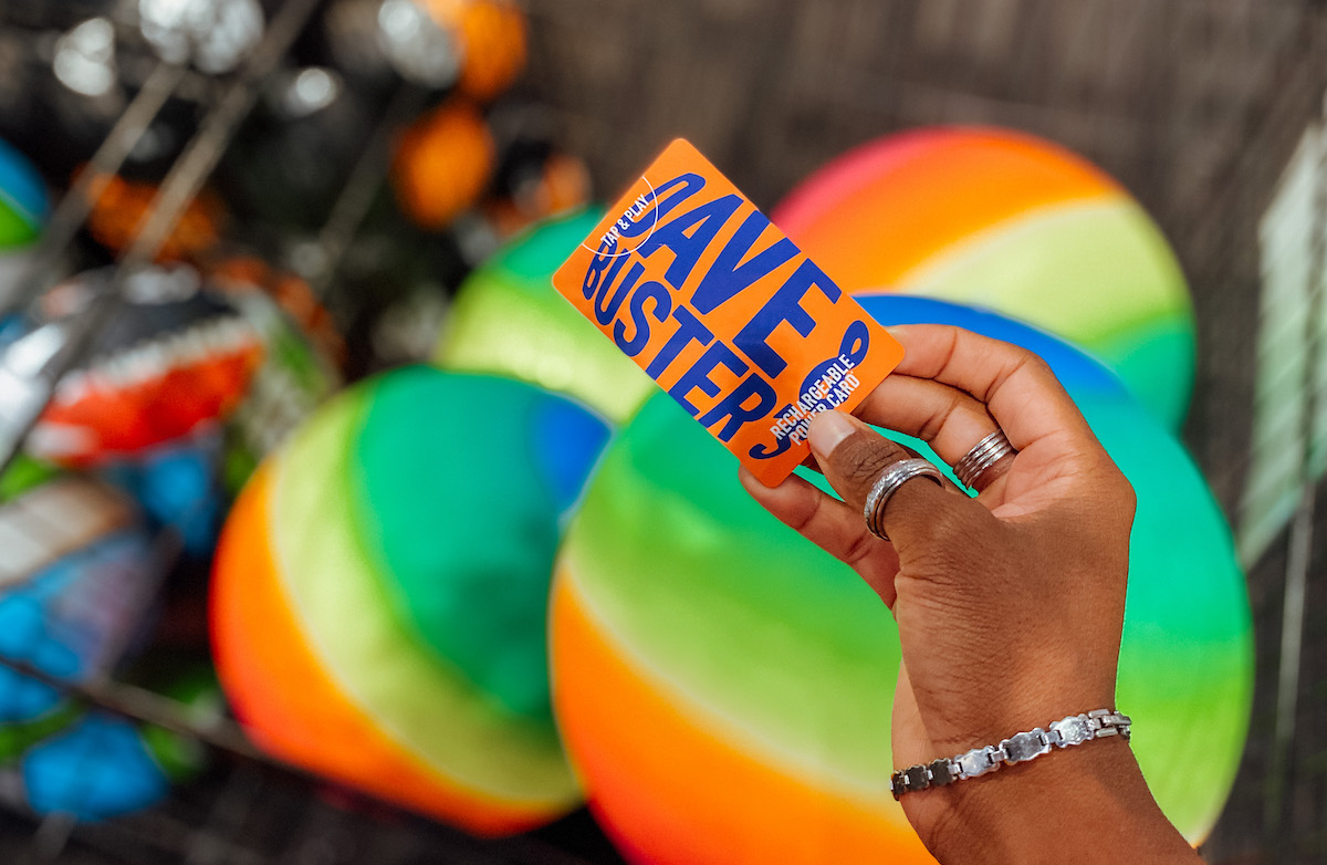 hand holding dave and busters powercard over rainbow colored balls