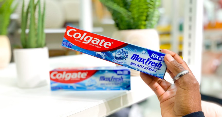 Hand holding Colgate Max Fresh toothpaste