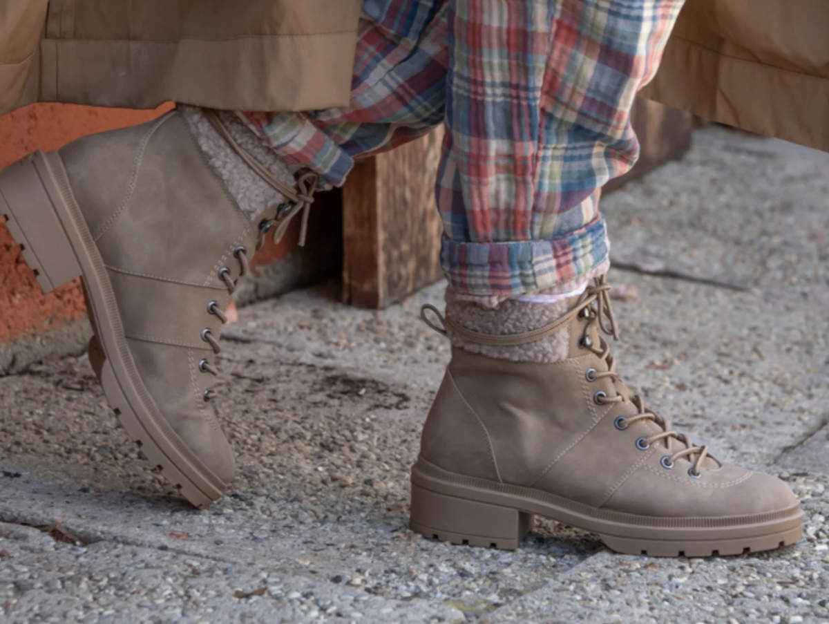 Person wearing a pair of taupe Rocket Dog boots and plaid pants