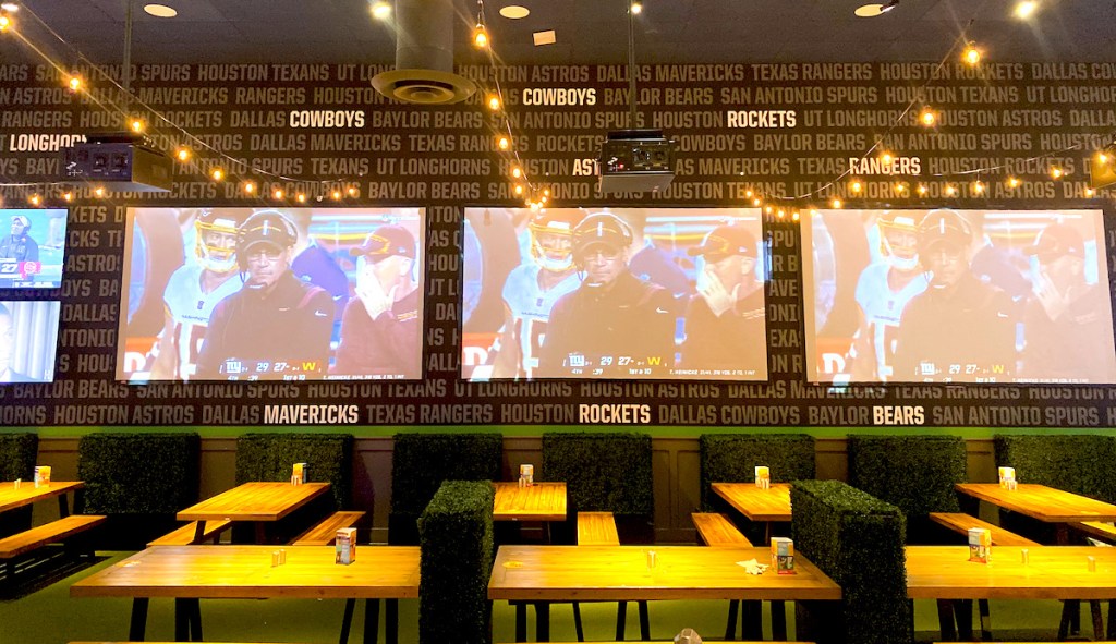 big screen tvs above picnic tables in restaurant 